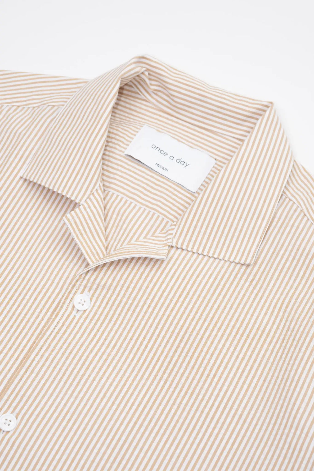 Beige striped camp collar shirt  in seersucker fabric on a white background