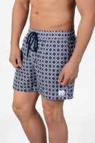 Man wearing blue patterned shorts in navy blue seersucker fabric and string closure on a plain background 