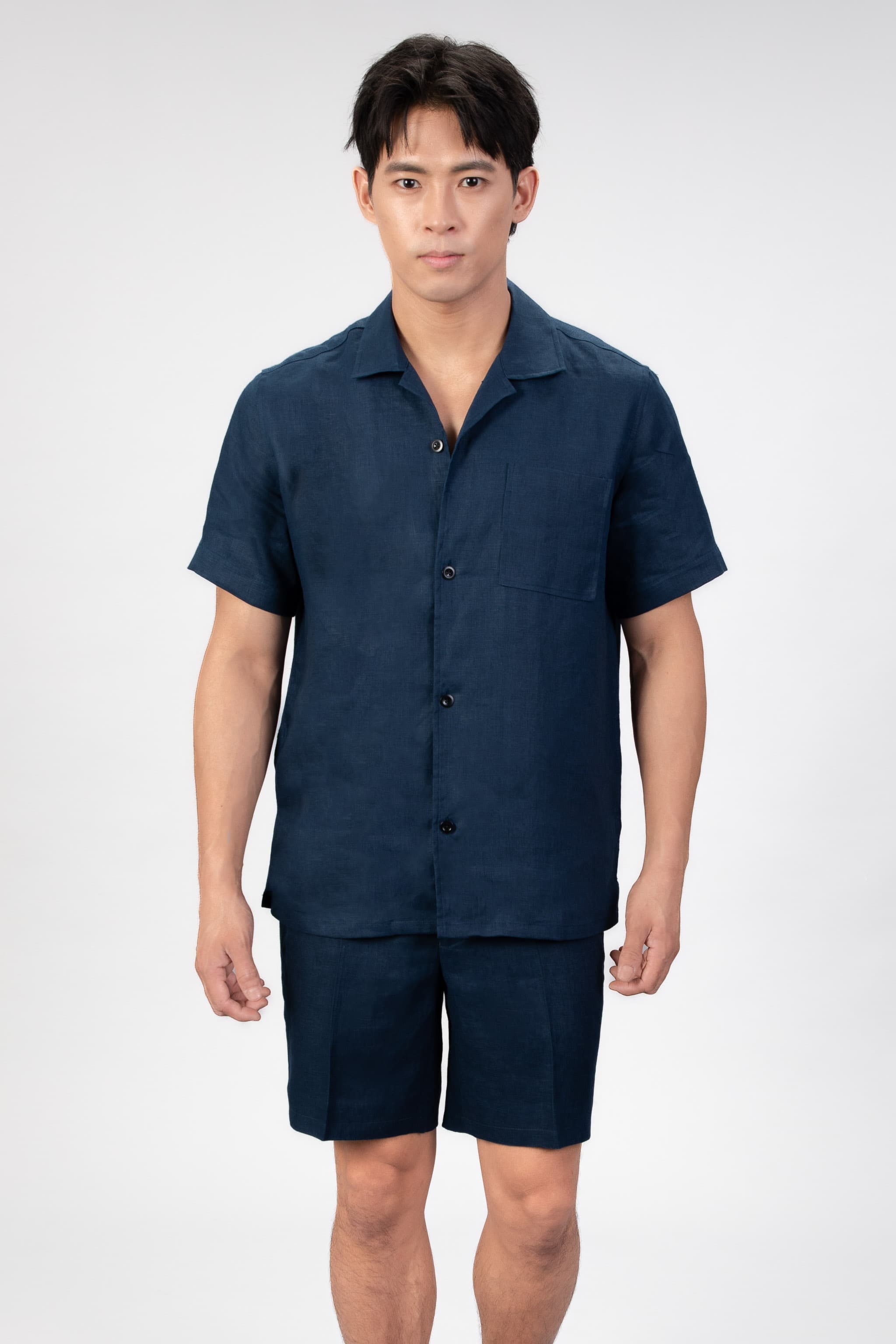 Man wearing a navy blue linen shirt and shorts set on a white background