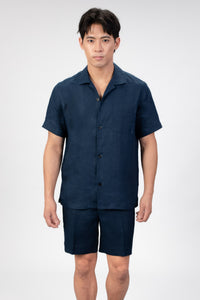 Man wearing a navy blue linen shirt and shorts set on a white background