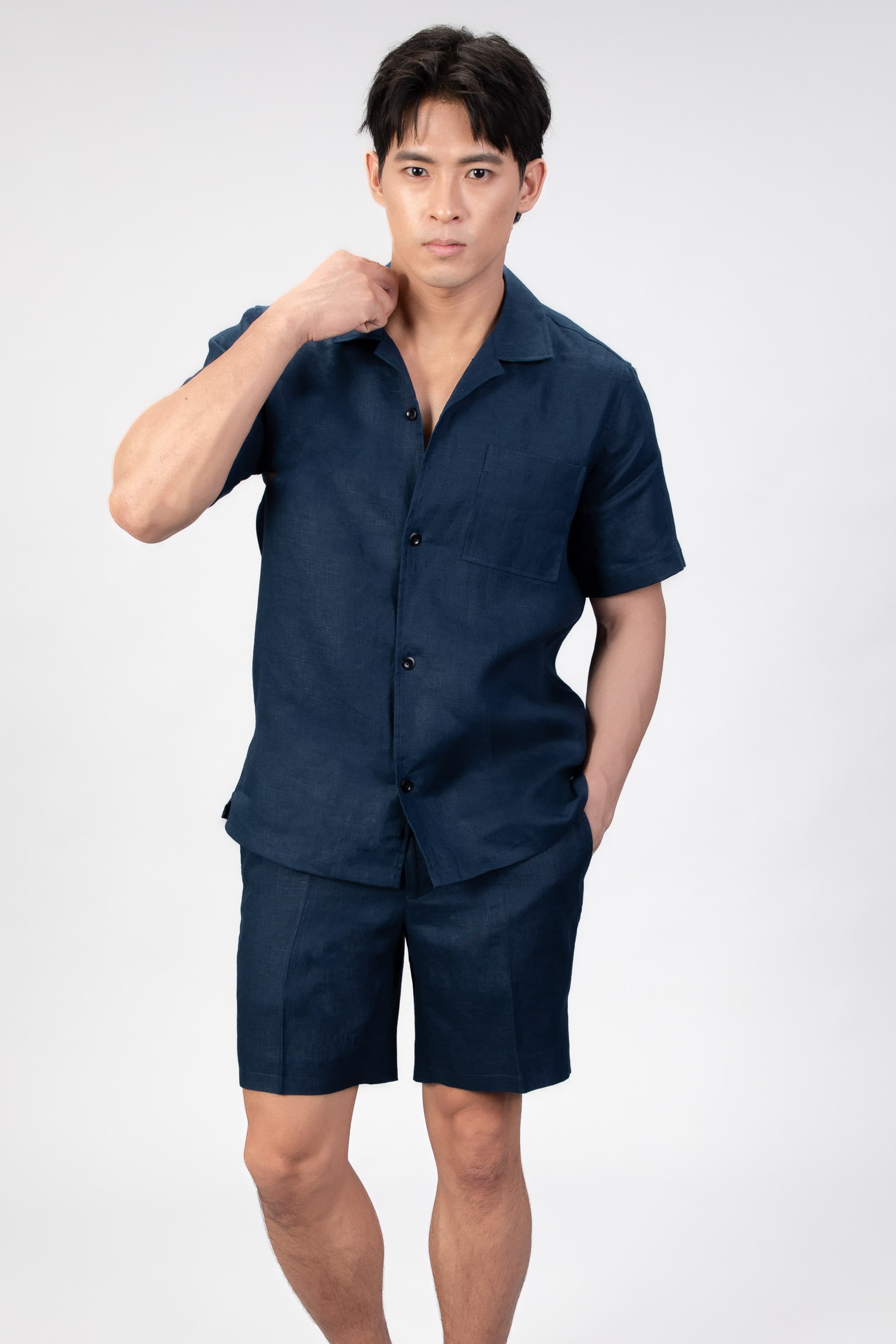 Man wearing a navy blue shirt and shorts set on a light gray background