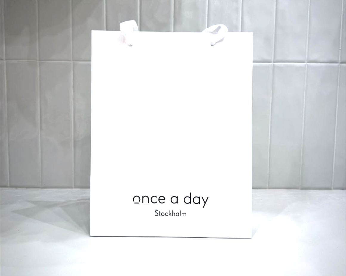 White paper bag with 'once a day Stockholm' text on a tiled wall background