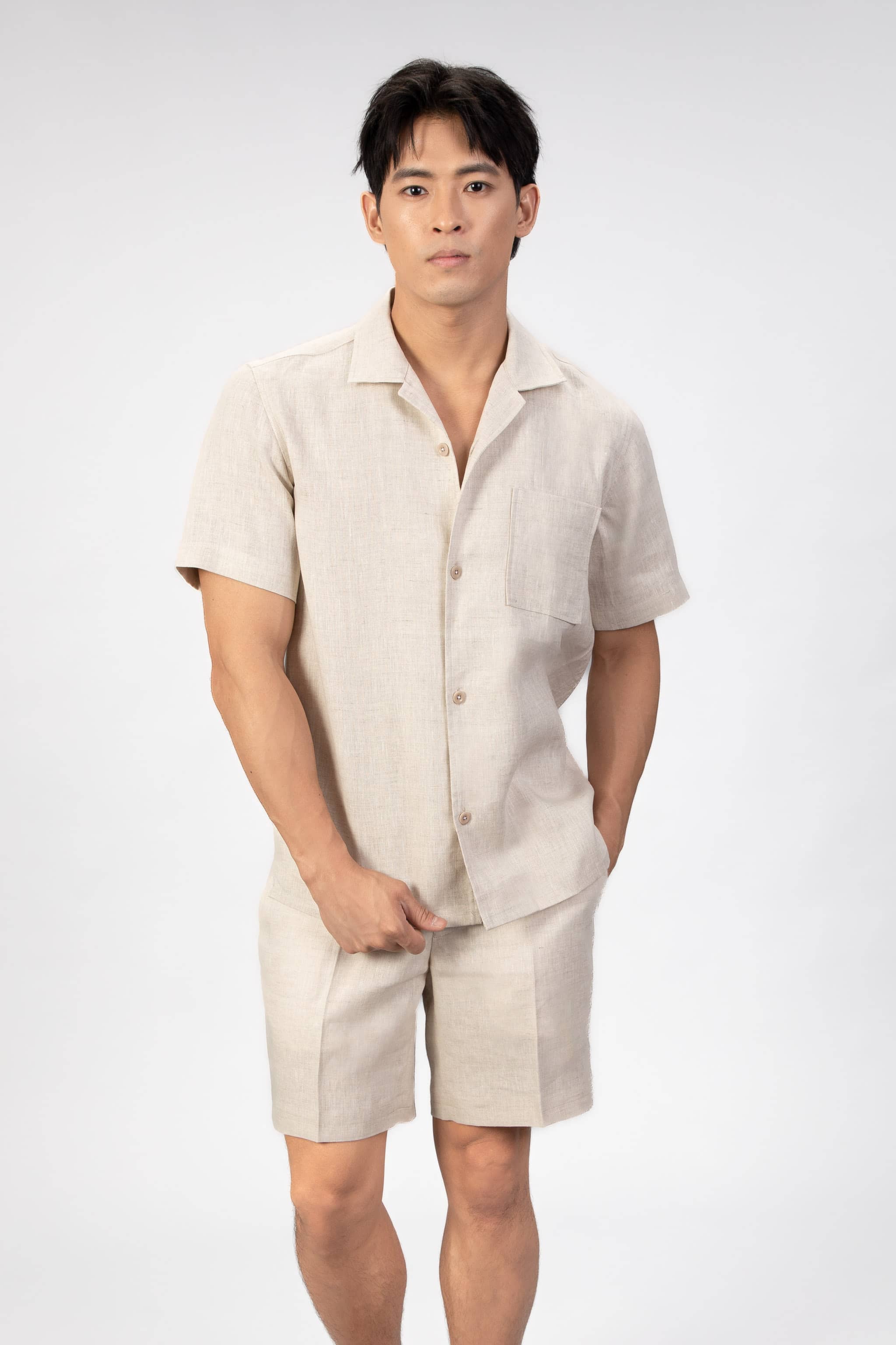 Man wearing a beige linen shirt and shorts set on a light background