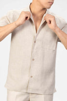 Man wearing a beige linen camp collar shirt and shorts set on a light background