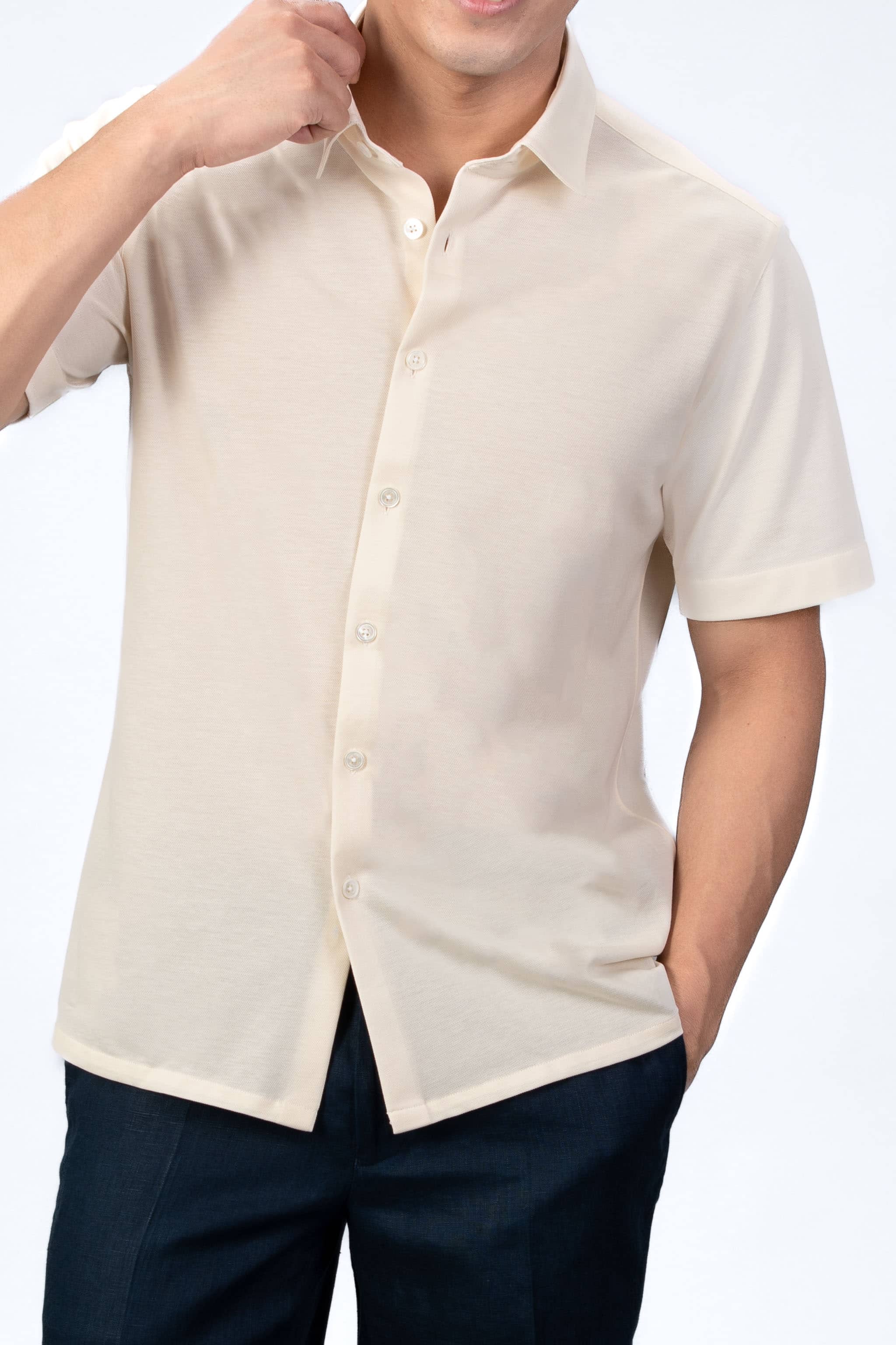 Man wearing a sand-beige piquet polo shirt sleeve shirt with linen navy shorts on a light gray background