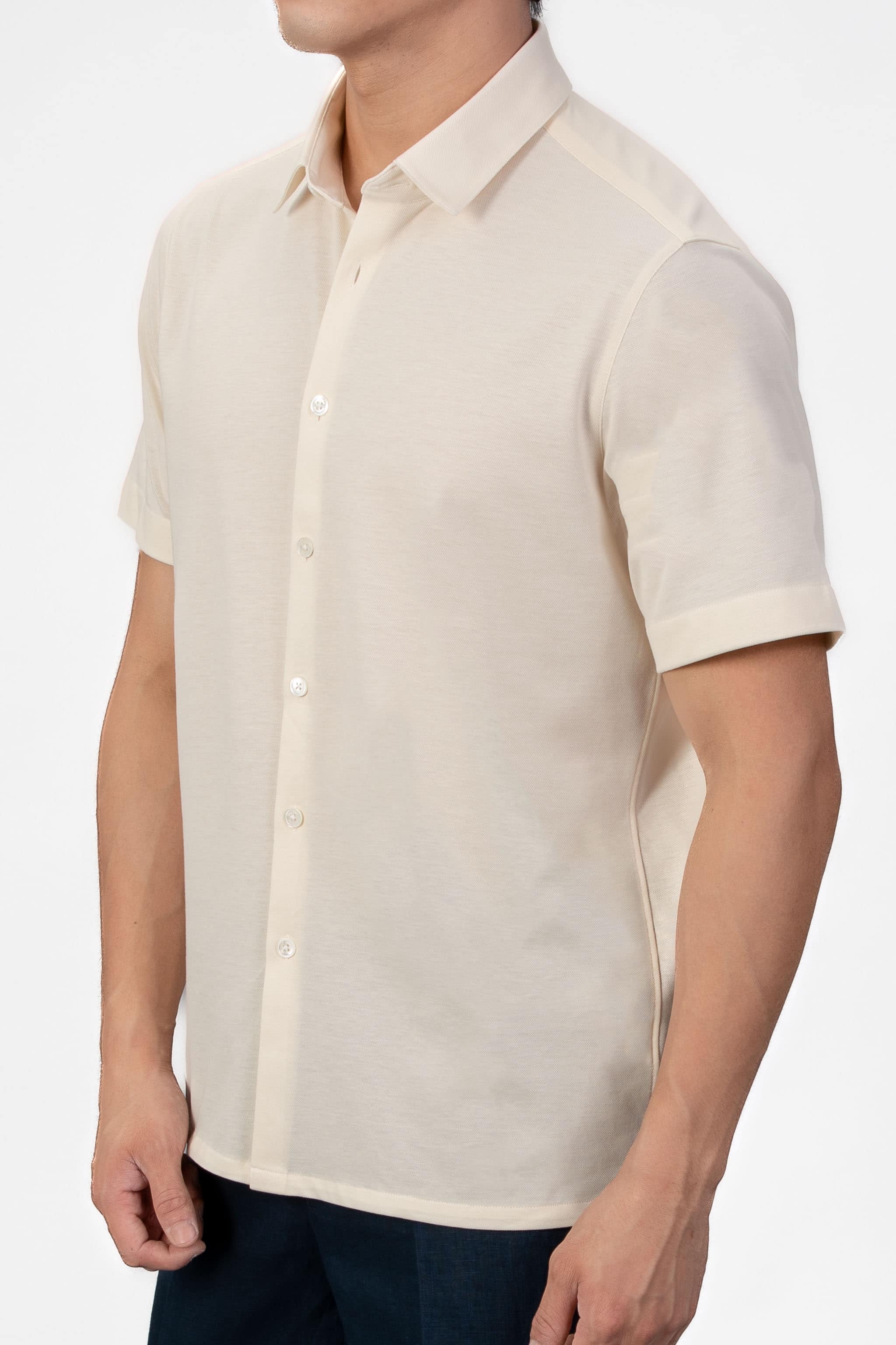 Man wearing a sand-beige piquet polo shirt sleeve shirt with linen navy shorts on a light gray background