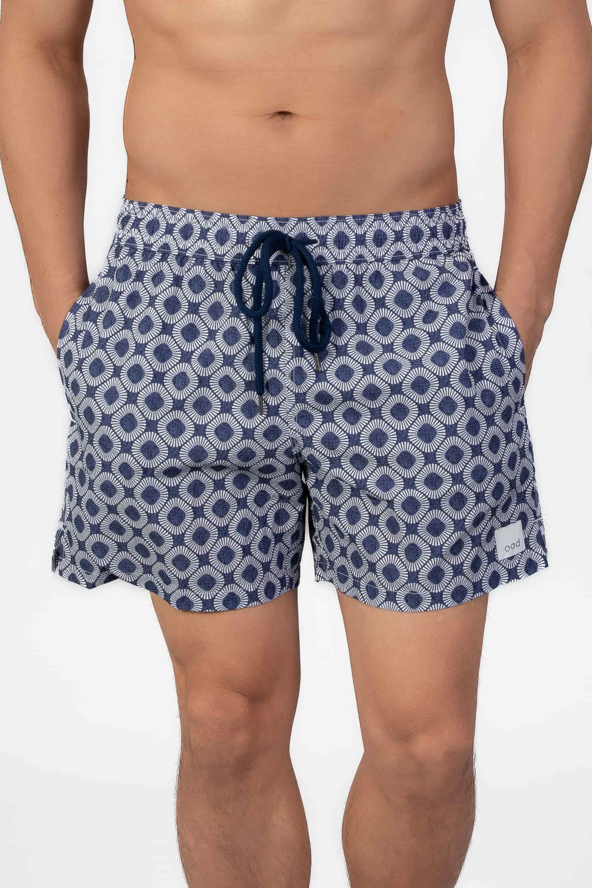 Man wearing blue patterned shorts in navy blue seersucker fabric on a plain background