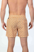 Person wearing stylish orange pattern seersucker swim shorts, back view showing the magnetic closure back pocket  and textured fabric.