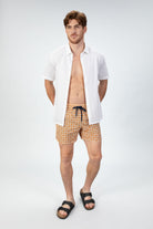 Person wearing stylish orange pattern seersucker swim shorts with a white seersucker shirt front view showing the magnetic closure back pocket  and textured fabric.