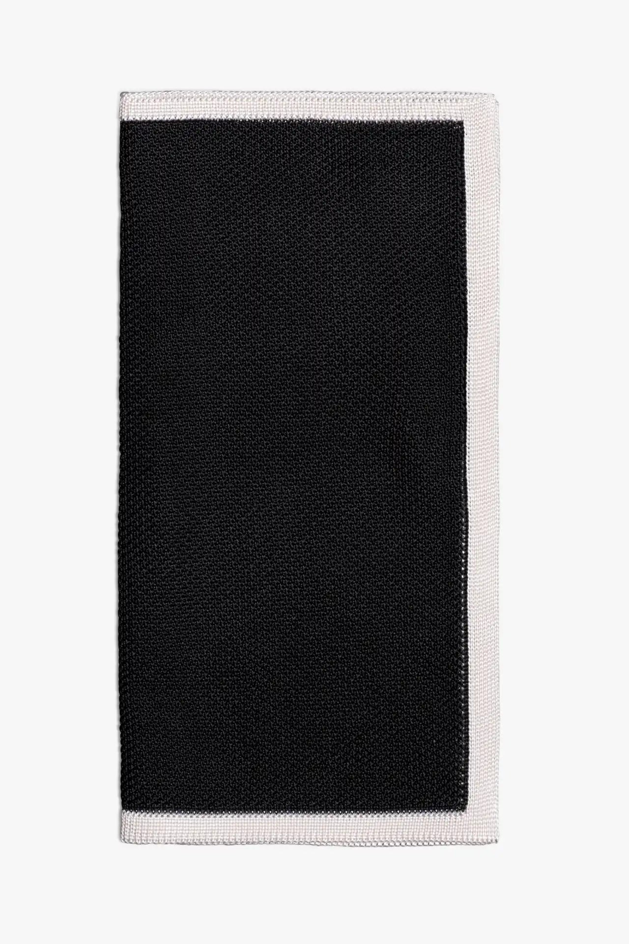 Black knitted pocket square with white frame. Made of silk in Italy paired with Matching tie.