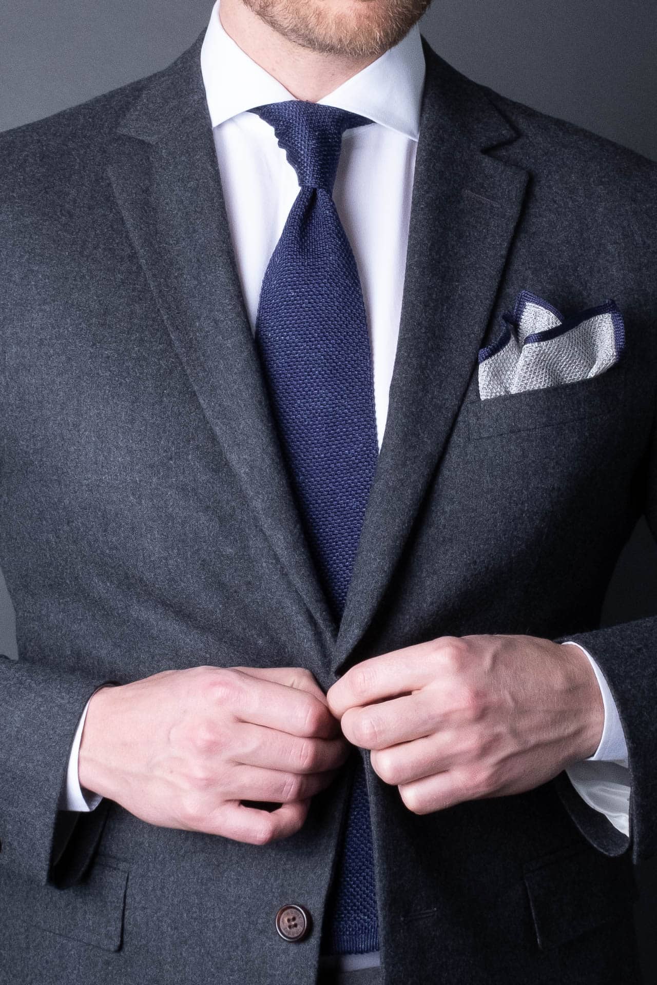 Gray knitted pocket square with navy blue boarder. Made of silk in Italy paired with Matching tie.