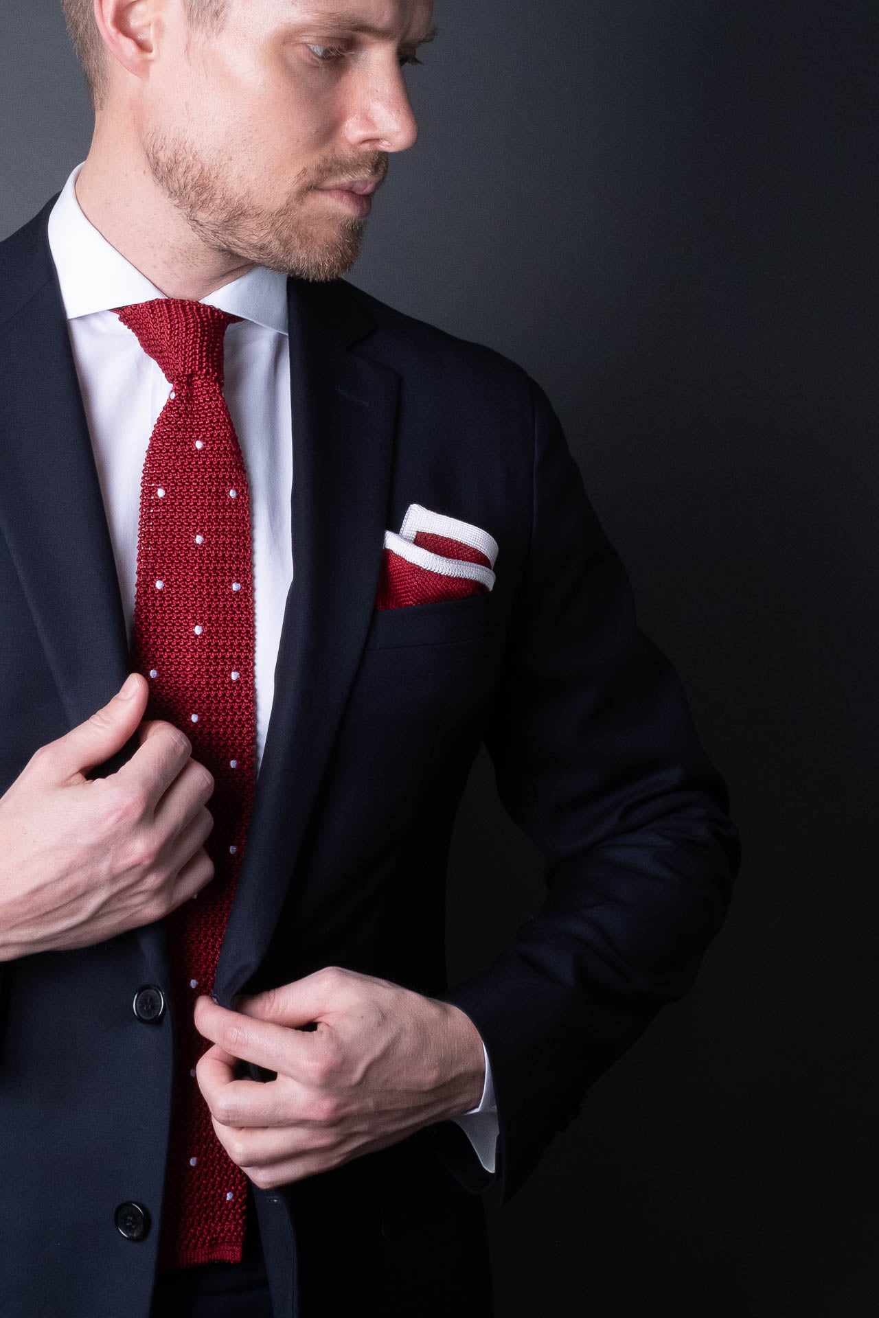 Red knitted pocket square with white frame. Made of silk in Italy paired with Matching tie.