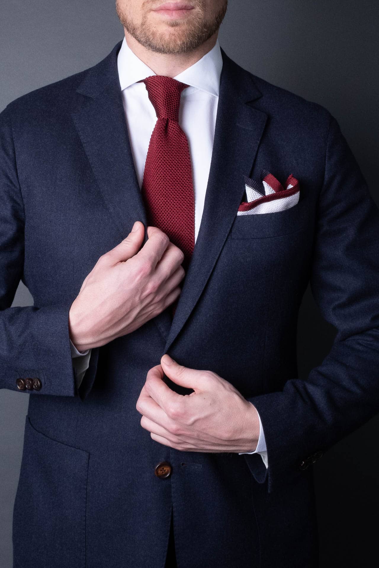 White pocket square with navy blue and red boarder. Knitted silk made in Italy with matching tie.