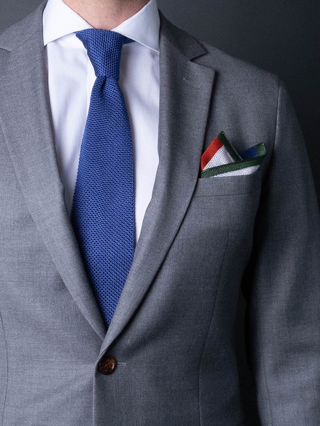 White pocket square with orange, blue and green boarder. Knitted silk made in Italy with matching tie.